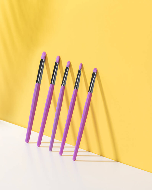 Pennelli per il trucco spazzole in polvere arrossiscono spazzole viola accessori trucco su uno sfondo giallo polvere movimento congelare bellezza cura di sé - Foto, immagini