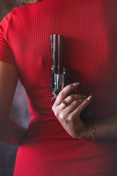 young woman in red dress holding gun pistol. crime concept. back view - Fotoğraf, Görsel