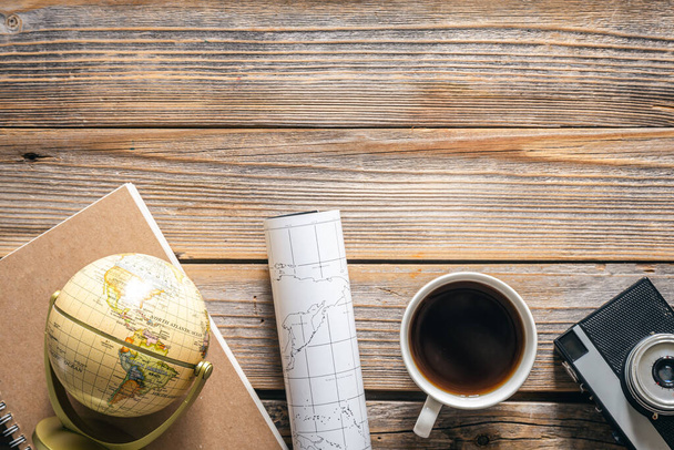 Wooden travel background with globe, map, retro camera and coffee, top view, copy space. - Photo, Image