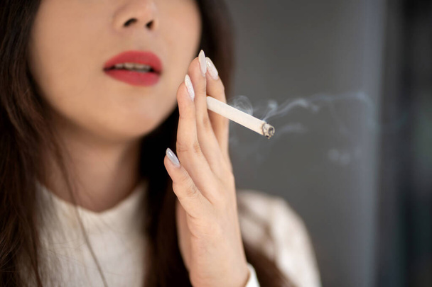 Jonge Aziatische vrouw die rookt. Het geneesmiddel is schadelijk voor de luchtwegen. - Foto, afbeelding