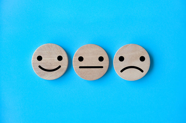 Happy, neutral, and sad emotion faces on wooden circle. Customer satisfaction and evaluation concept. - Foto, afbeelding