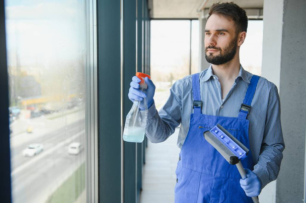 Male janitor cleaning window in office. - Foto, imagen