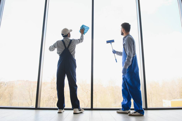 multiethnic professional cleaners in uniform washing large windows in office. - Photo, Image