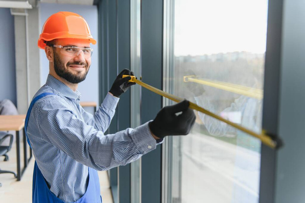 Worker installing plastic window indoors - Foto, Imagen