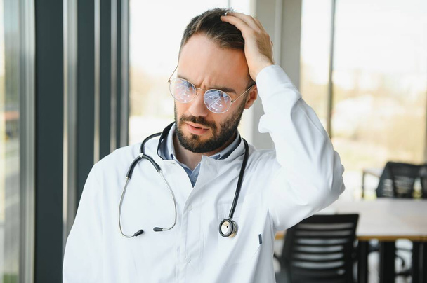 Stressed male doctor. Mid adult male doctor working long hours. Overworked doctor in his office. Not even doctors are exempt from burnout. - Valokuva, kuva