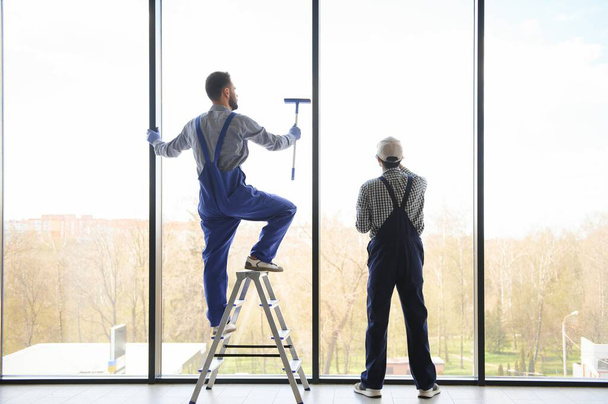 back view of multicultural professional workers washing large panoramic windows in office. - Fotoğraf, Görsel