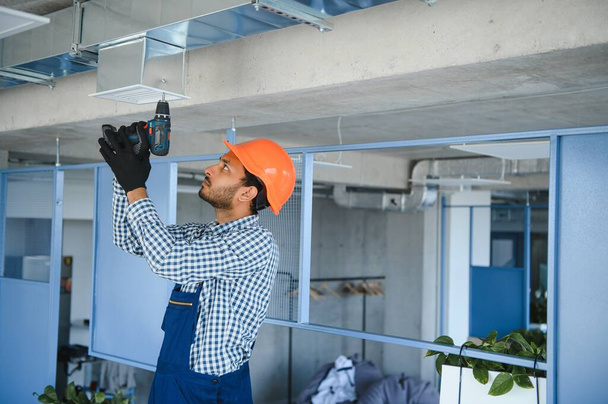 Professional technician maintaining modern air conditioner indoors. Space for text. - 写真・画像