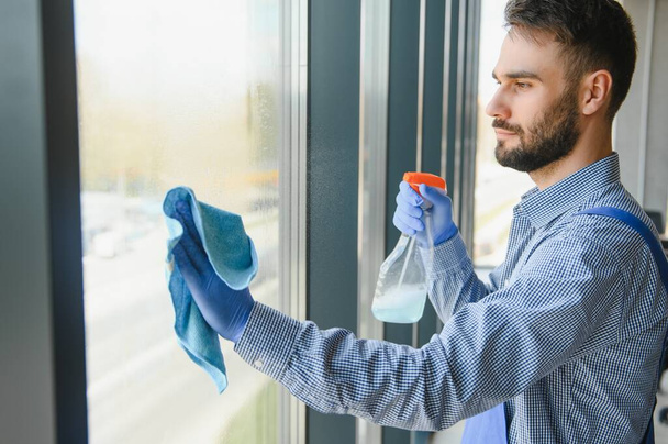Male worker washing window glass - Фото, изображение