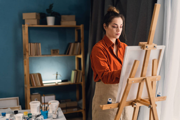 Χαριτωμένη γυναίκα καλλιτέχνης ζωγραφική εικόνα στο εργαστήριο, ζωγράφος κάνει έργα τέχνης στο στούντιο τέχνης. Αντιγραφή χώρου - Φωτογραφία, εικόνα