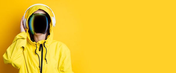 Молода жінка в окулярах кіберпанку з навушниками в жовтій куртці на жовтому тлі. Банер. - Фото, зображення