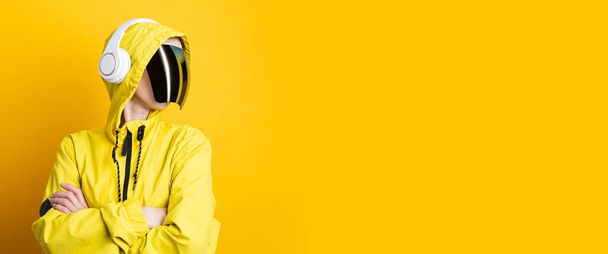 Młoda kobieta w cyberpunkowych okularach ze słuchawkami w żółtej kurtce na żółtym tle. Sztandar. - Zdjęcie, obraz