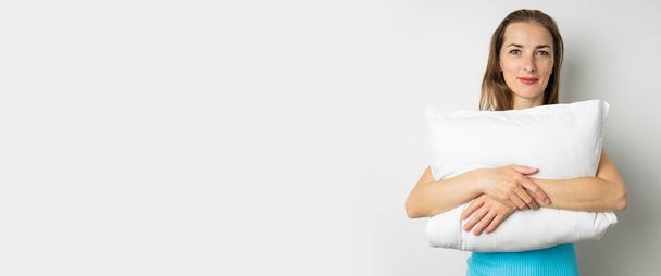 Smiling young woman in tank top holding pillow on white background. Banner. - Fotografie, Obrázek
