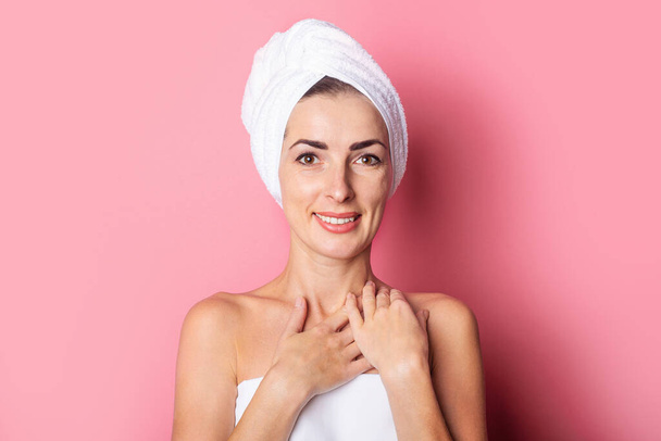 skin care. Smiling girl with a towel on her head on a pink background. - Фото, изображение