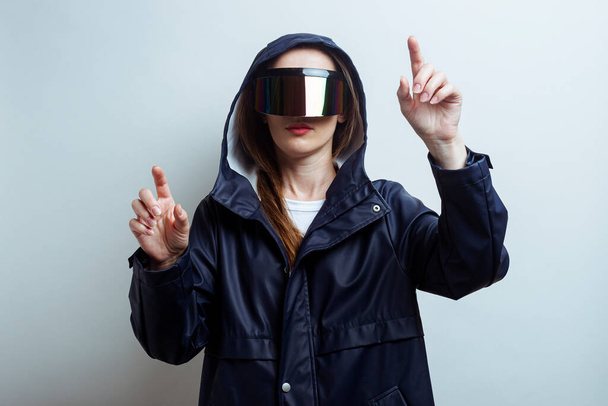 Young woman in virtual reality glasses pressing fingers on a touchscreen on a light background. - Photo, Image