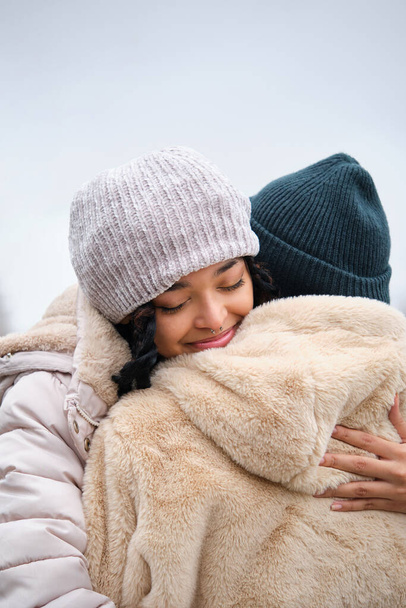 Dominican lesbian couple hugging with affection and love at street in a winter day. - Photo, Image