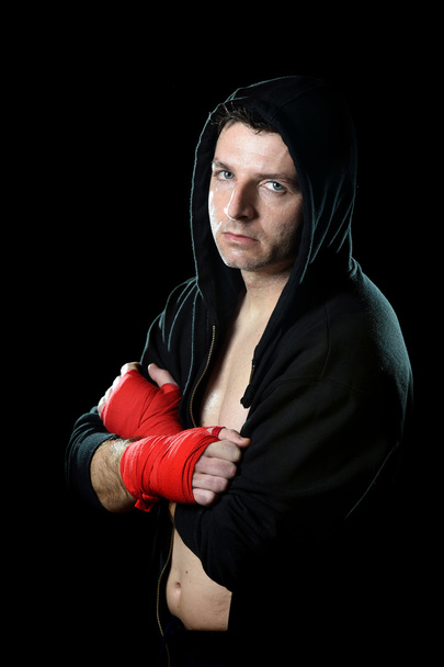 Man in boxing hoodie jumper with hood on head with wrapped hands wrists ready to fight - Photo, Image