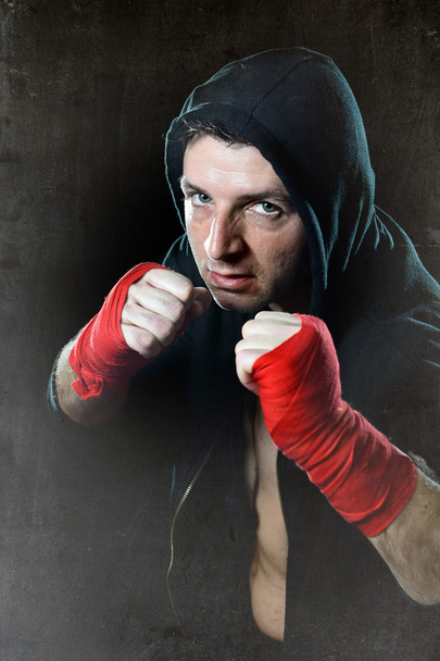 Man in boxing hoodie jumper with hood on head with wrapped hands wrists ready for fighting - Photo, Image