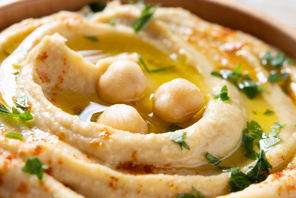 Hummus de garbanzo en un tazón de madera adornado con perejil, pimentón y aceite de oliva - Foto, imagen