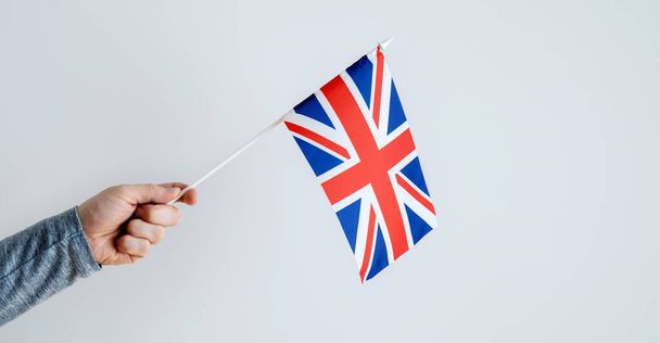 Close-up, man's hand holding the UK flag. Place for text about learning English. - Photo, image