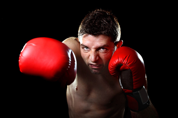 agresivo luchador hombre entrenamiento sombra boxeo con guantes de combate rojo lanzando golpe derecho vicioso
 - Foto, Imagen