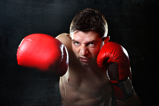 агресивний боксерський чоловік в червоних бойових рукавичках кидає злий правий удар
 - Фото, зображення