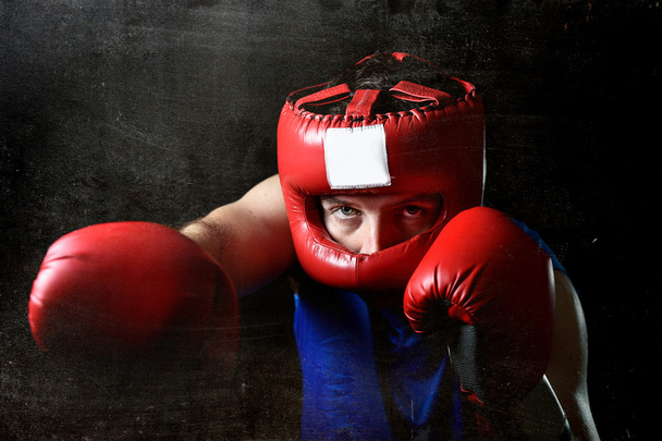 Amateur boxer man fighting with red boxing gloves and headgear protection - Photo, Image
