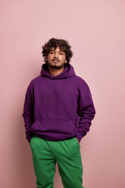Fashionable young Indian man looking at camera while standing against pink background - Fotoğraf, Görsel