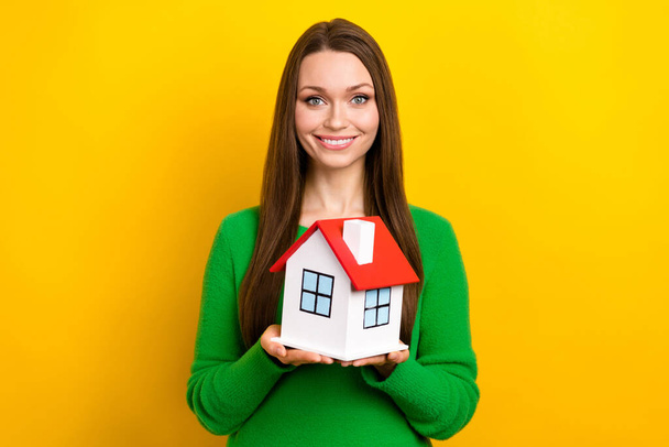 Portrait of pretty positive lady beaming smile arms hold little house isolated on yellow color background. - Foto, immagini