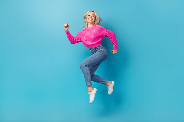 Full body photo cadre of active young girl running wear pink sweater jeans fast speed hurry fashion week isolated on blue color background. - Фото, зображення