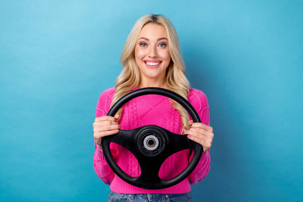 Portrait of toothy beaming positive woman with wavy hairdo wear pink pullover holding steering wheel isolated on blue color background. - Foto, immagini