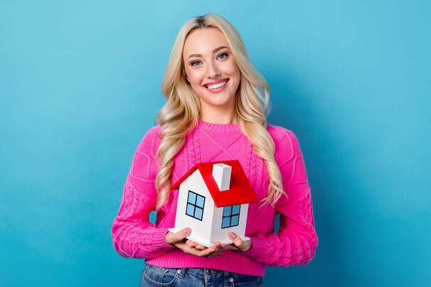 Photo of optimistic nice good mood person with curly hairdo dressed knit sweater hold small house isolated on blue color background. - Фото, изображение