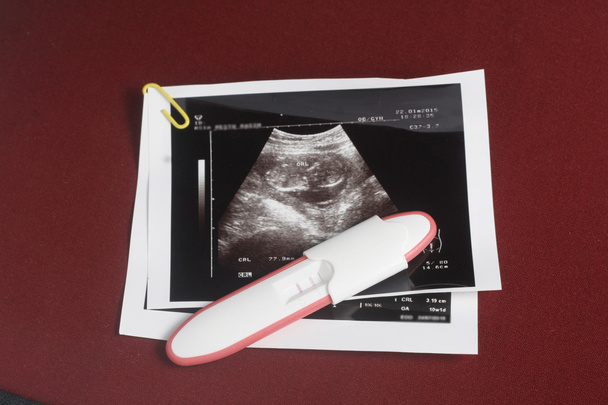Hamilelik testi paketini koyu kırmızı arka plan - Fotoğraf, Görsel