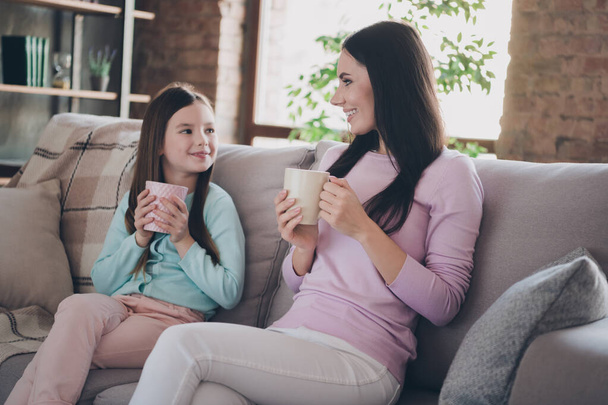 Photo of two cute lovely happy ladies sitting sofa discussing first school day relax rest spend time together inside room indoors. - Foto, Bild