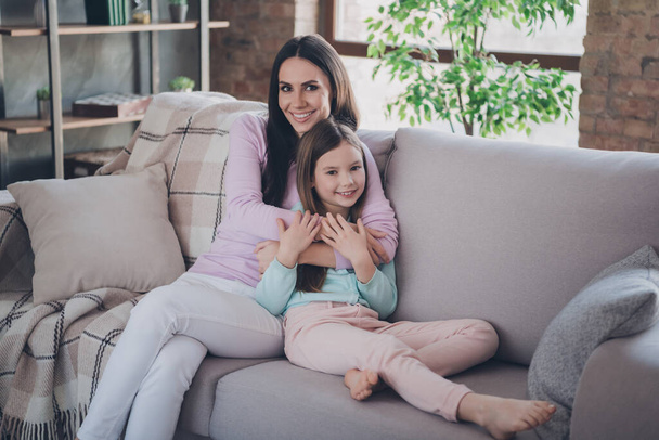 Photo of pretty mommy holding her preteen daughter spend weekend together sit comfortable sofa home apartment flat house. - Valokuva, kuva