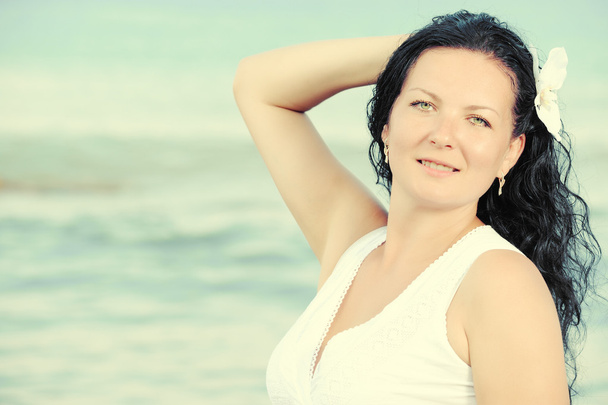 Nainen valkoisessa auringonpuvussa meren rannalla.
. - Valokuva, kuva