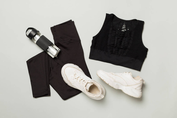 Schwarzes Fitnessstudio-Outfit auf farbigem Hintergrund, Draufsicht - Foto, Bild