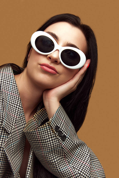 Fashionista. Portrait with beautiful, stylish woman, wearing sunglasses and looking away with upset face over brown studio background. Concept of beauty, fashion, trends, human emotions, ad - Фото, изображение