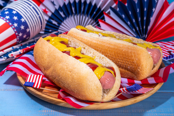 USA Patriotic picnic holiday hot dogs.  American patriotic hot dog on wooden board plate, with USA flag. Celebrating Independence day on 4th July, Memorial or Veteran Day - Photo, Image