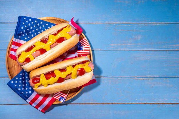 USA Patriotic picnic holiday hot dogs. Perro caliente patriótico americano en placa de madera, con bandera de EE. UU. Celebración del Día de la Independencia el 4 de julio, Memorial o Día del Veterano - Foto, Imagen