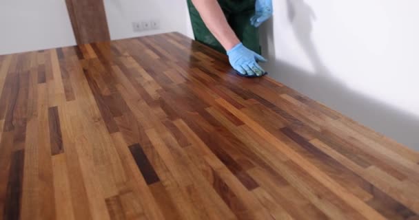El carpintero procesa la superficie de madera con barniz para saturar el color. Hombre en guantes de goma pule mesa nueva para sala de estar cámara lenta - Metraje, vídeo