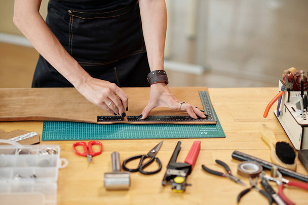 Manos de artesano cortando pieza de cuero en rayas delgadas - Foto, imagen
