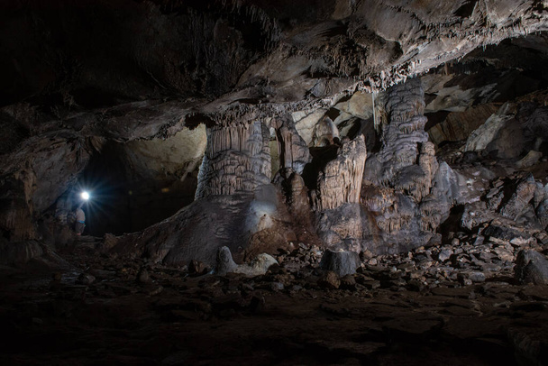 cavers inspect the cave with a light bulb looking for stalactites and stalagmites - Foto, imagen