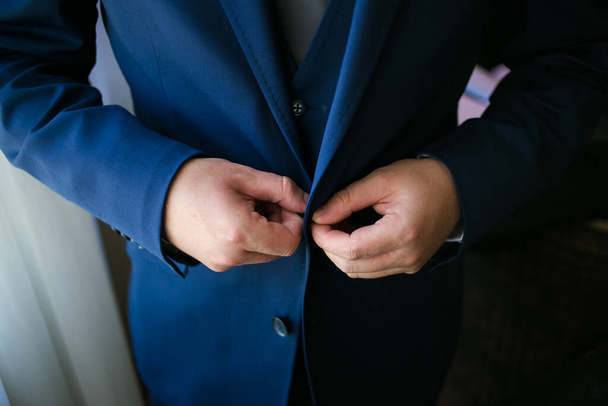 This captivating image showcases the groom's wedding attire, including his suit, shoes, and cufflinks, as he gets dressed for his big day. The photograph highlights the intricate details of the groom's ensemble, creating a beautiful composition that  - Foto, Bild
