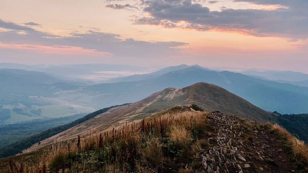 Sunset in mountains. Natural mountain landscape with illuminated misty peaks, foggy slopes and valleys, blue sky with orange yellow sunlight. Amazing scene from Bieszczady Mountains in Poland - Foto, imagen