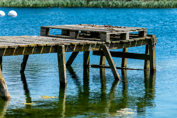 A tavi nyugalom csábítása: lenyűgöző kilátás egy fából készült mólóra, amely elmerül egy fenséges tó nyugodt szépségében. - Fotó, kép