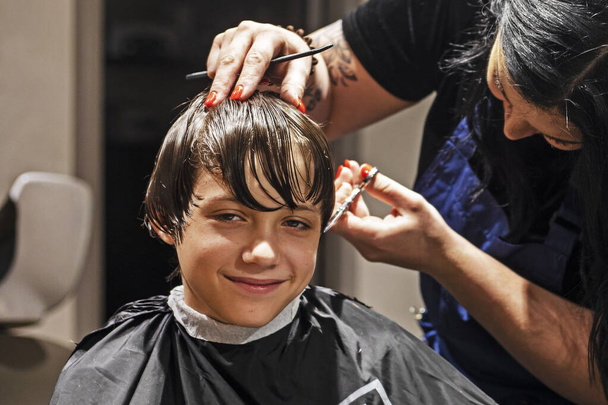 barbiere taglia le estremità dei capelli bagnati e puliti a un ragazzo con le forbici - Foto, immagini