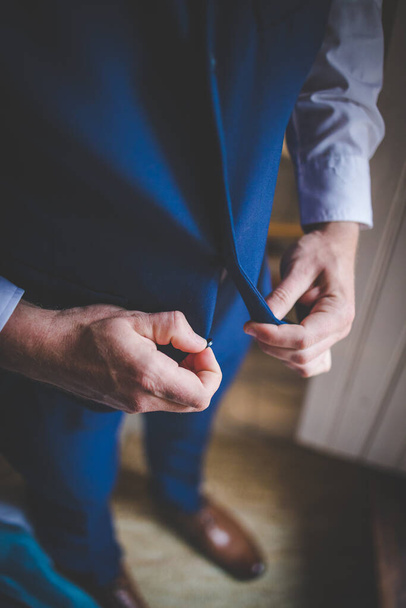 This captivating image showcases the groom's wedding attire, including his suit, shoes, and cufflinks, as he gets dressed for his big day. The photograph highlights the intricate details of the groom's ensemble, creating a beautiful composition that  - Photo, image