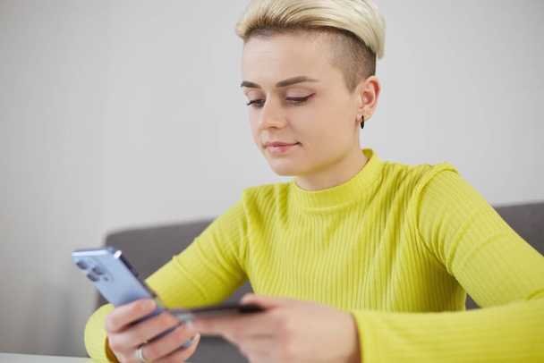 Young woman shopping online with a smartphone. Female person making a credit card purchase in a mobile application - Photo, image