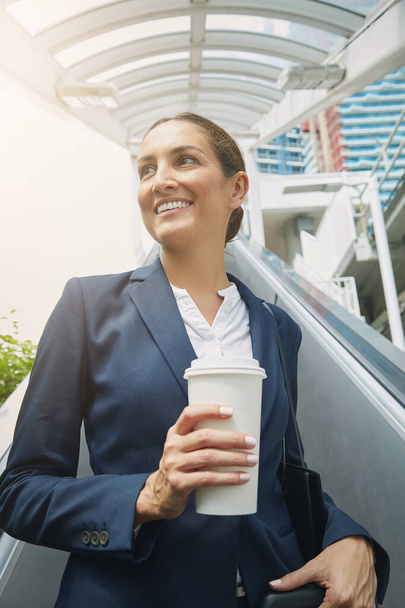 Kaffee rundet ihren Arbeitsweg ab. eine junge Geschäftsfrau trinkt auf dem Weg zur Arbeit einen Kaffee - Foto, Bild