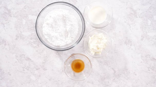 Flat lay. Step by step. Ingredients in a glass mixing bowl to prepare cream cheese frosting. - Foto, Bild